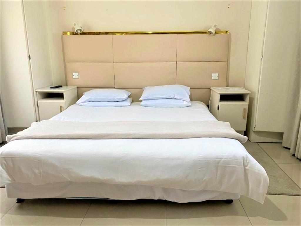 a bedroom with a large bed with two pillows at Luxurious suite with outdoor pool - 2171 in Bulawayo