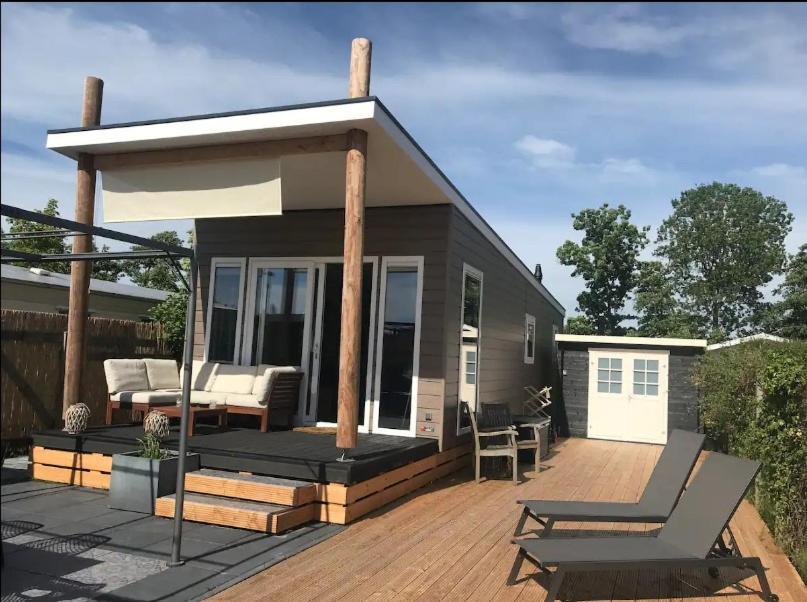 a small house with a deck and a patio at Chalet 561 op Recreatiepark De Wielen in Sint Maarten