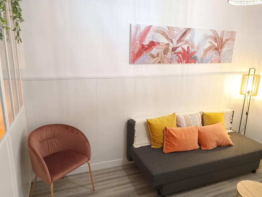 - un canapé avec des oreillers colorés et une chaise dans la chambre dans l'établissement Appartement climatisé au cœur de Montpellier, à Montpellier