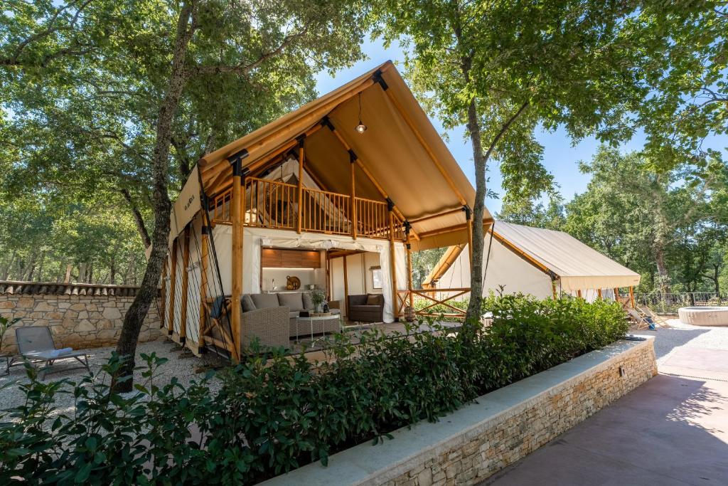 a house with a wrap around porch in the woods at Banki Green Istrian Village - Holiday Homes & Glamping Tents in Bašići