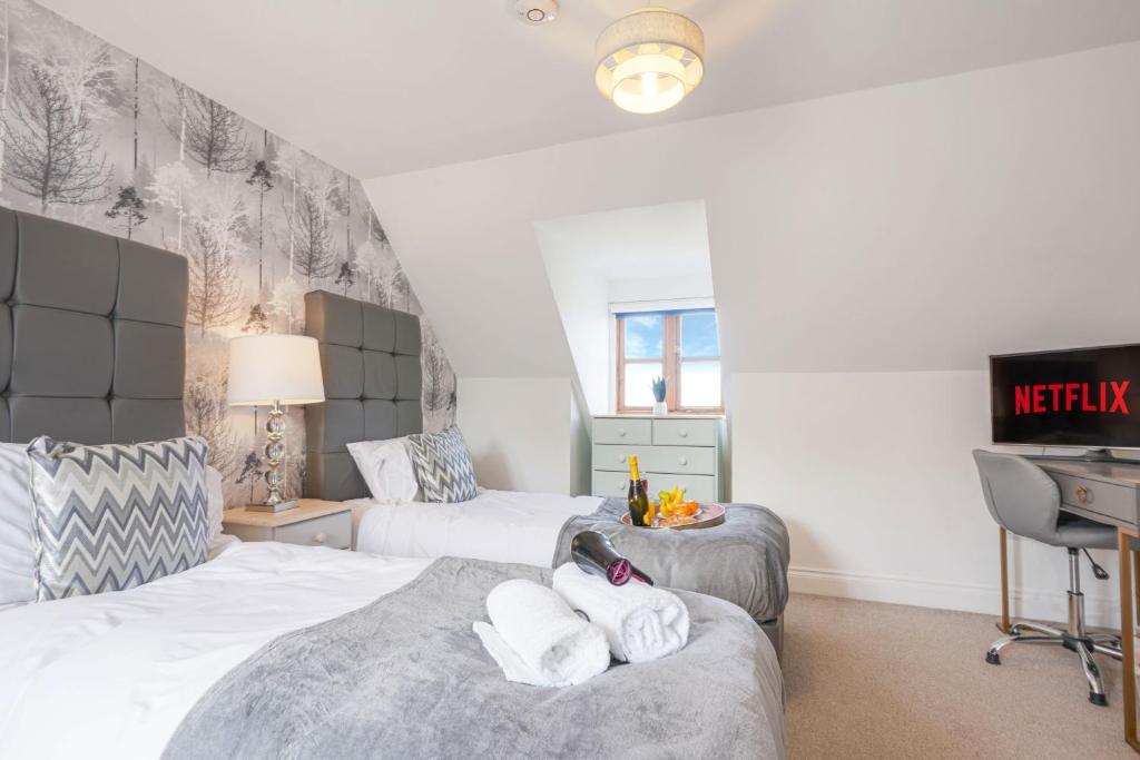 a bedroom with two beds and a desk and a tv at Loughton House - Central Location - Free Parking, Private Garden, Super-Fast Wifi and Smart TVs by Yoko Property in Milton Keynes
