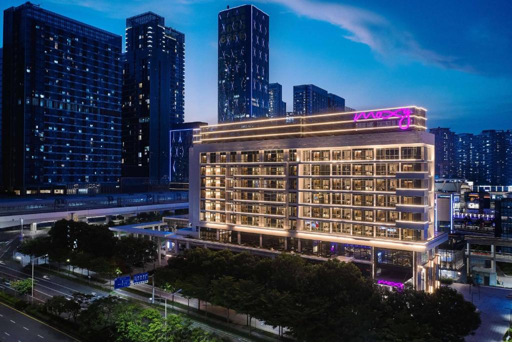 a rendering of a hotel in a city at night at Moxy Shenzhen North Station in Shenzhen