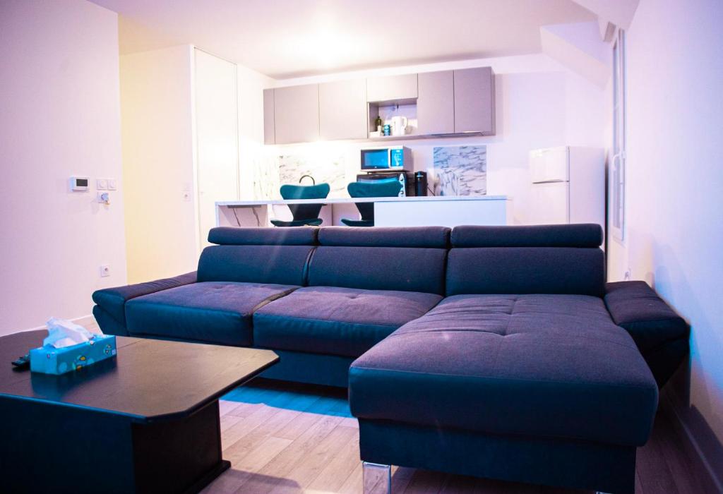 uma sala de estar com um sofá azul e uma mesa em Colocation de Janvier à Fin Juin une chambre disponible em Linas