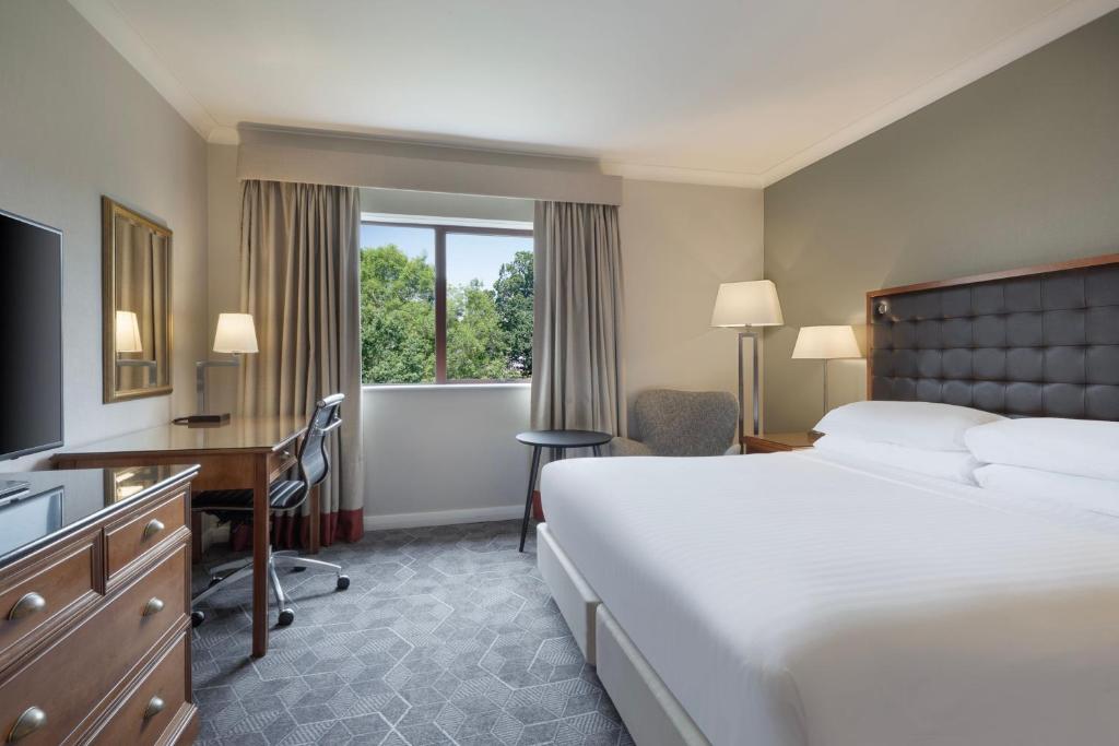 a hotel room with a bed and a desk and a window at Delta Hotels by Marriott Waltham Abbey in Waltham Abbey