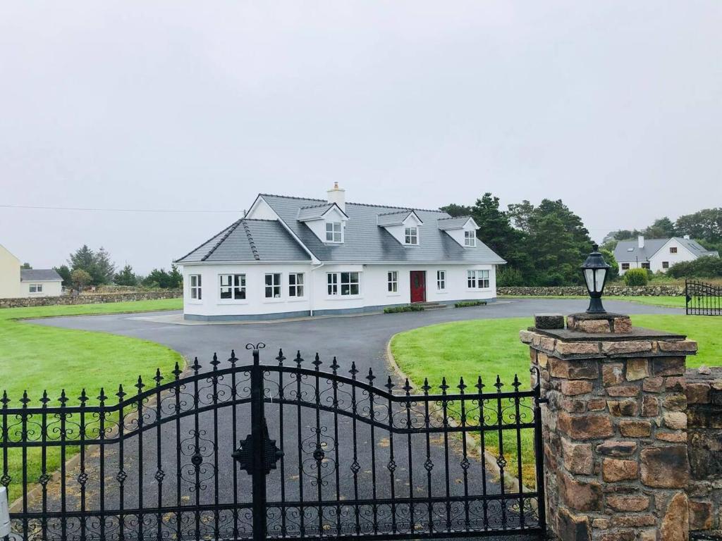 ein großes weißes Haus mit einem Tor davor in der Unterkunft Connemara. 3 Bedroom, 8 bed, Holiday home in Galway