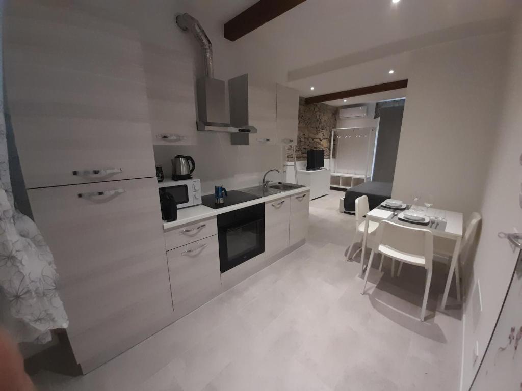 uma cozinha com armários brancos, uma mesa e uma sala de jantar em Appartamento Elia em La Spezia