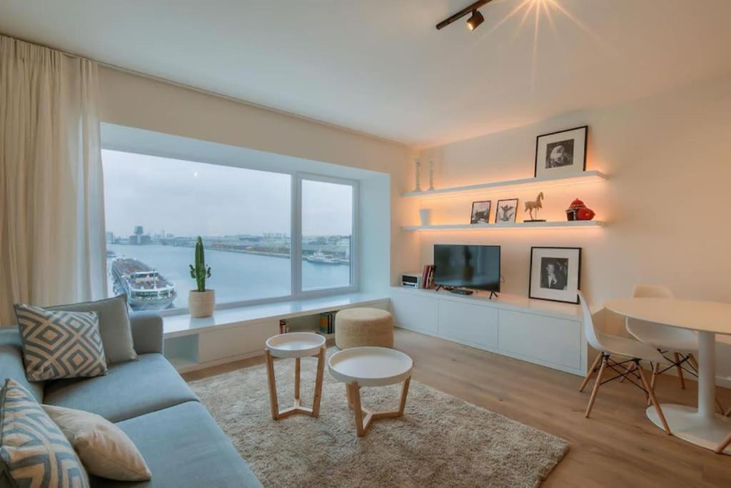 a living room with a blue couch and a large window at Unique Appartment view MAS! in Antwerp