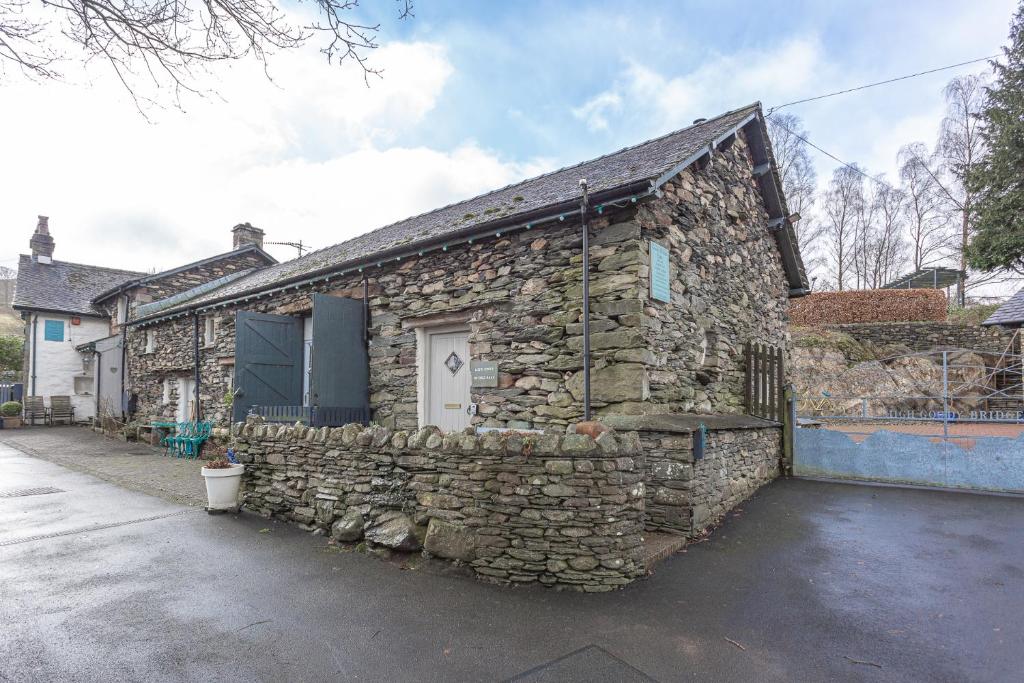 a stone house with a stone wall at Goody Bridge Barn in Grasmere