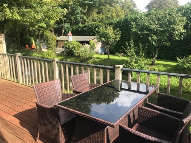 un patio con tavolo e sedie su una terrazza in legno di The Riverside Apartment on Cheddar Bridge Apartments a Cheddar