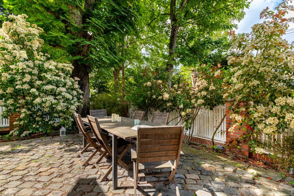 a wooden table and chairs on a brick patio at Double Appartements 2&amp;3 210 sqm up to 18 guests, Villa des Ammonites in Meudon