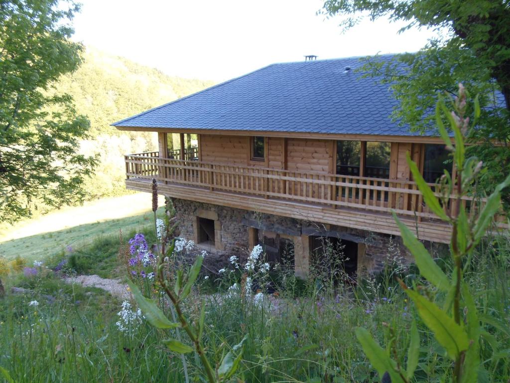 a large wooden house with a deck in a field at CHALET BOIS PLEINE NATURE 6 PLACES in Sainte-Eulalie-dʼOlt