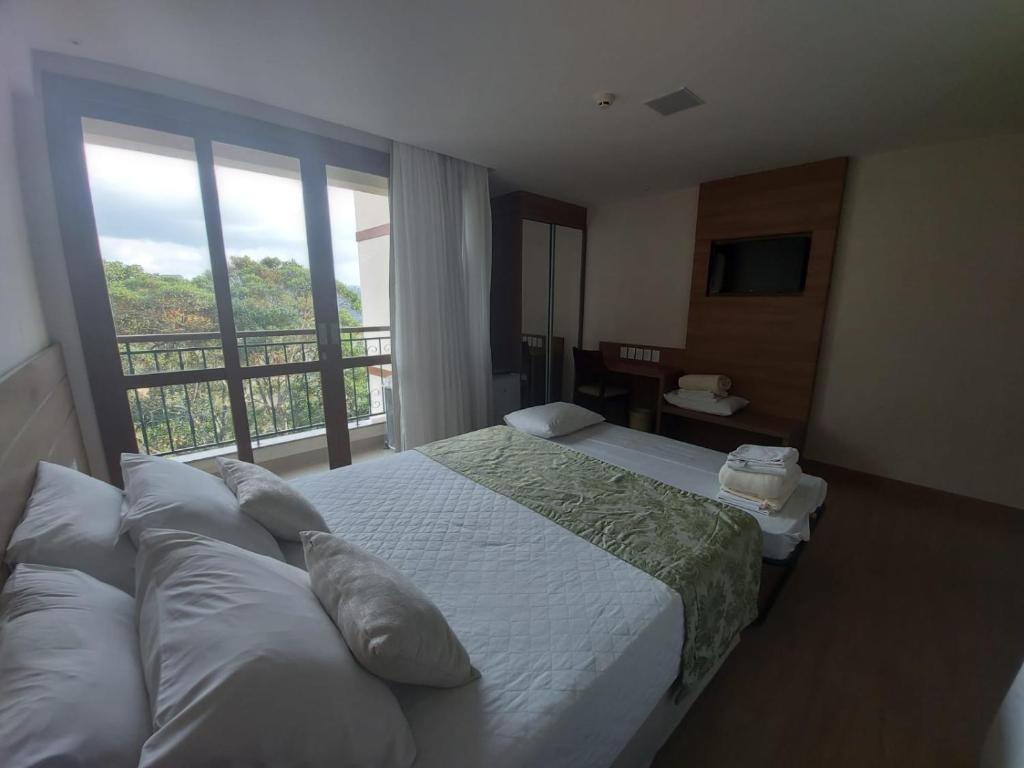 Habitación de hotel con cama y balcón en Vista Azul Suites, en Vítor Hugo