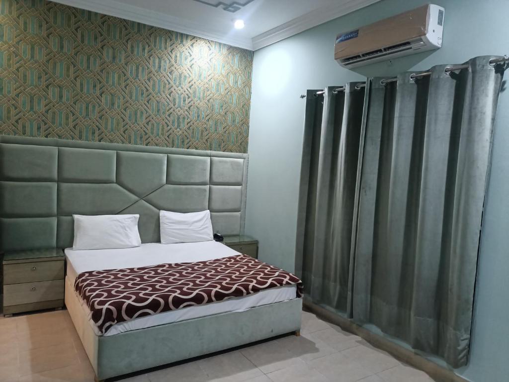 1 dormitorio con 1 cama y una pared con cortinas en Hotel Taj Palace Multan, en Multán