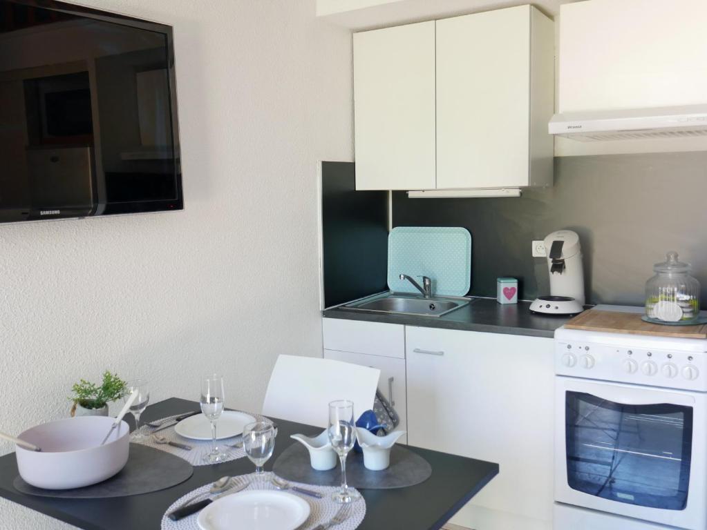 une cuisine avec une table avec des assiettes et des verres dessus dans l'établissement Maison de plein pied à Barcares, au Barcarès