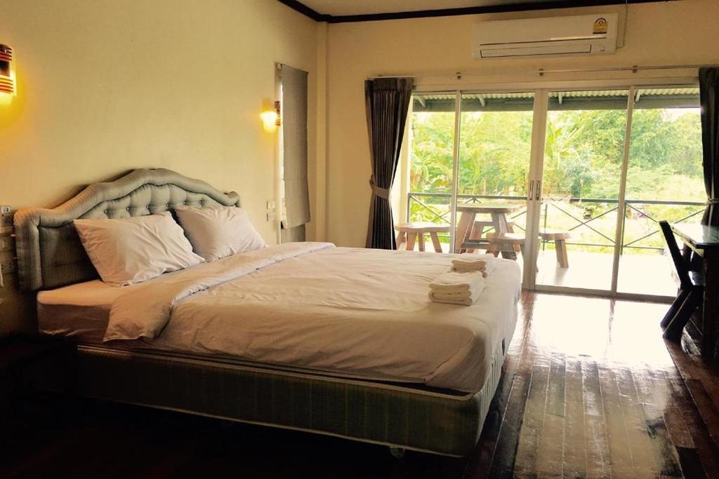 a bedroom with a large bed with a large window at Be Fine Sabuy Hotel and Resort in Suratthani