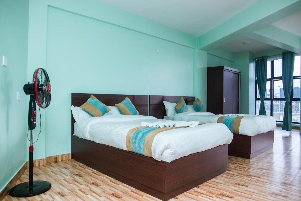 two beds in a room with blue walls and a fan at Yaksa Hotel Pvt. Ltd. in Kathmandu