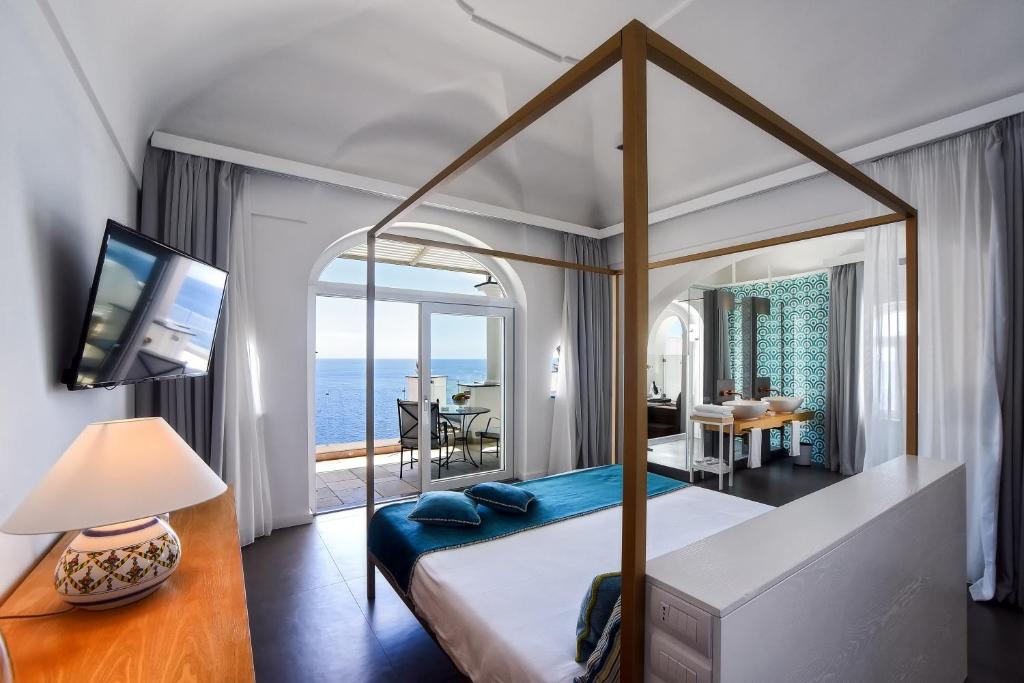 a bedroom with a canopy bed with a view of the ocean at Hotel Montemare in Positano