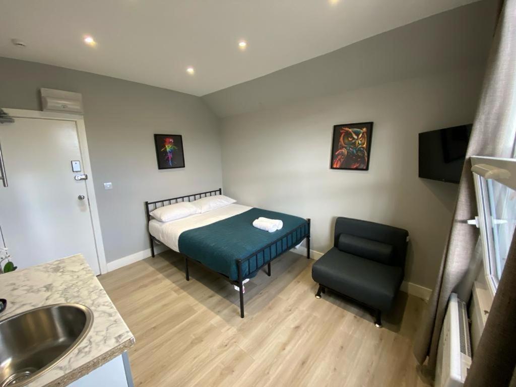 een slaapkamer met een bed, een stoel en een wastafel bij Holloway Suites - Next To Emirates Stadium - Private Bathroom - Shared Kitchen in Londen