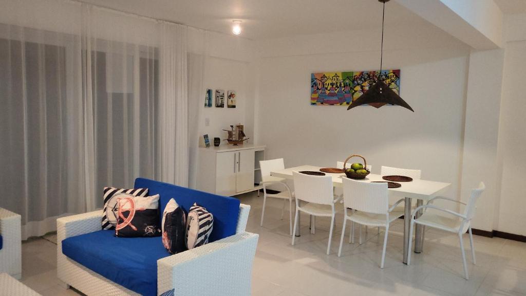 uma sala de estar com uma mesa e um sofá azul em Apartamento Particular de 03 suítes, Resort Treebies, Praia de Subauma - Ba em Entre Rios