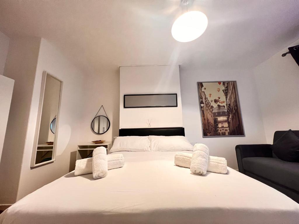 - une chambre avec un grand lit blanc et un canapé dans l'établissement Rooms in Bethnal Green, à Londres