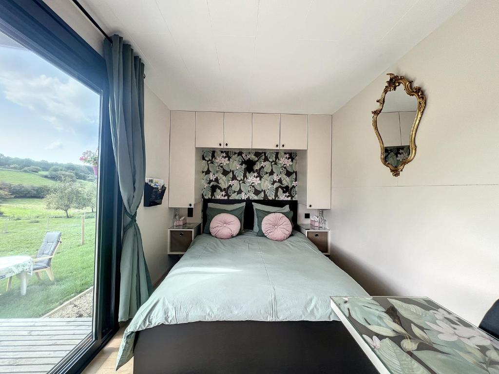 Schlafzimmer mit einem Bett mit rosa Kissen und einem Fenster in der Unterkunft La Bricole in Dinant