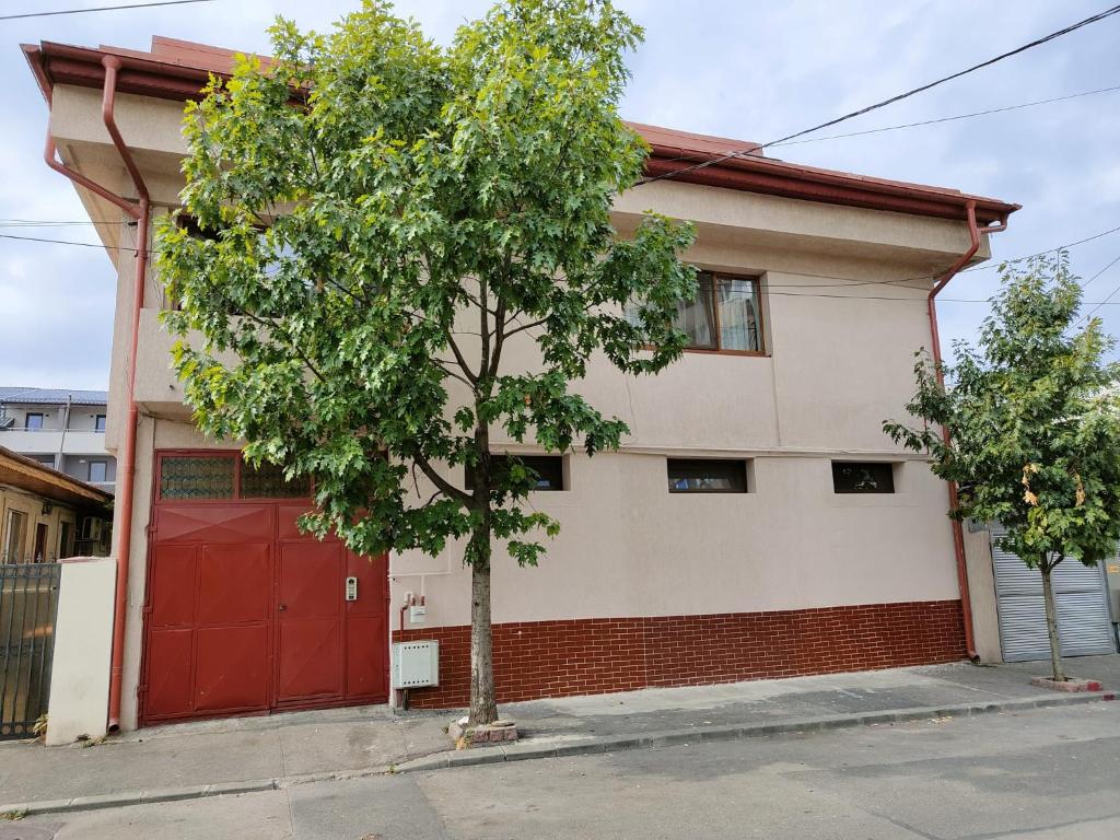 un árbol frente a una casa con un garaje rojo en Z Villa, en Bucarest