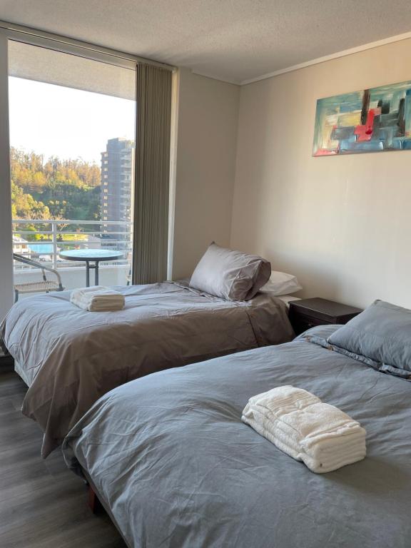 two beds in a hotel room with a window at Departamento Vista Privilegiada in Concepción