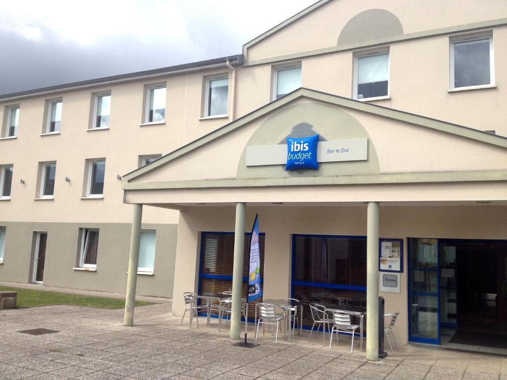 un edificio con mesas y sillas delante de él en ibis budget Bar le Duc en Bar-le-Duc