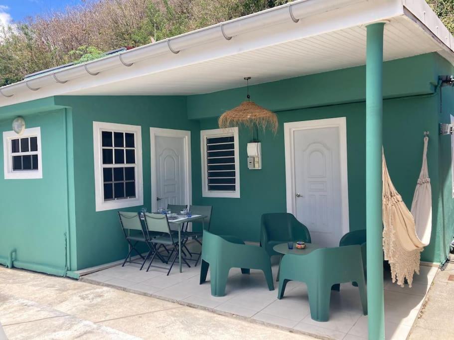 Maison Les Abymes - Plage à 50m في Le Prêcheur: منزل أخضر مع طاولة وكراسي على فناء