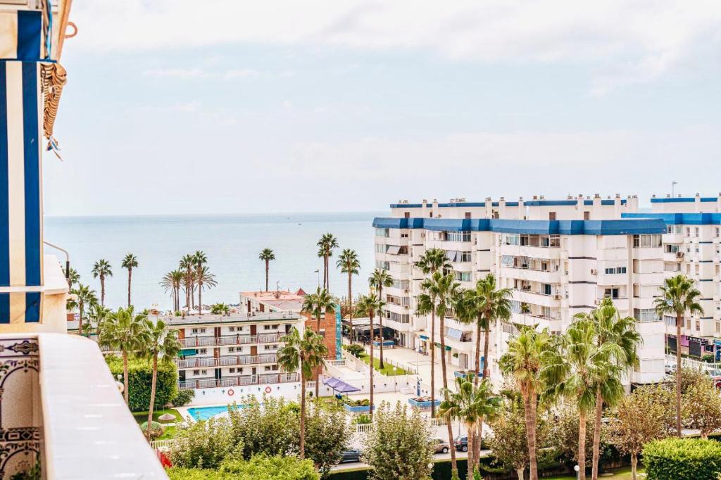 uma vista para um edifício com palmeiras e o oceano em Andalucia Beach em Benalmádena