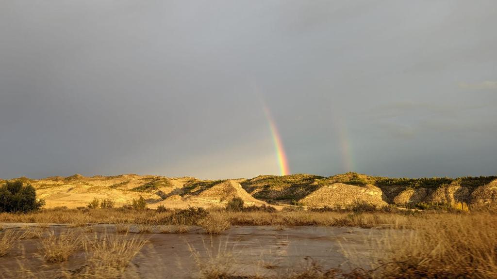 een regenboog in de lucht boven een veld met een rivier bij Loft Carriones in Castilléjar