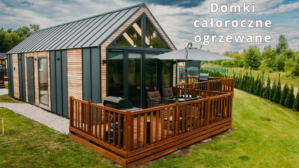 a cabin with an outdoor deck with an umbrella at LUXURY CAMP - 150 m od Suntago Park in Grabce-Towarzystwo