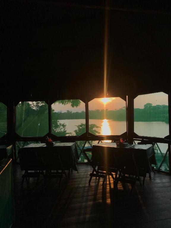 een groep tafels met de zonsondergang op de achtergrond bij Ipanema Lodge in Careiro