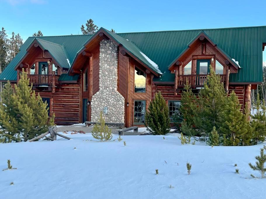 una cabaña de madera con nieve delante en The Wyoming Lodge and Game Room, en Dubois