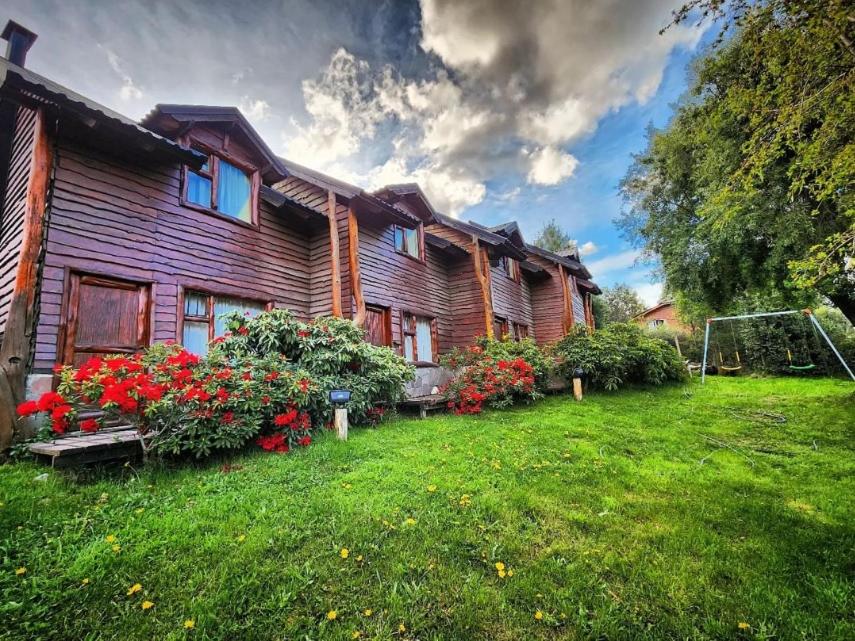 a log house with flowers in the yard at Los Condores Bariloche in San Carlos de Bariloche