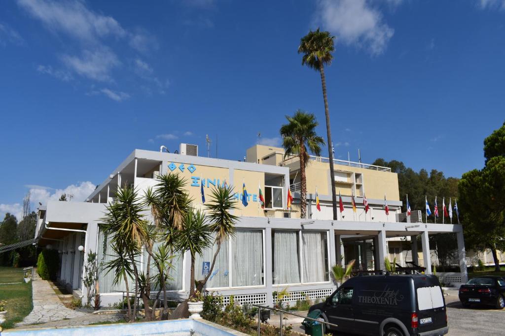 un edificio blanco con palmeras delante en Hotel Theoxenia, en Mesolongi