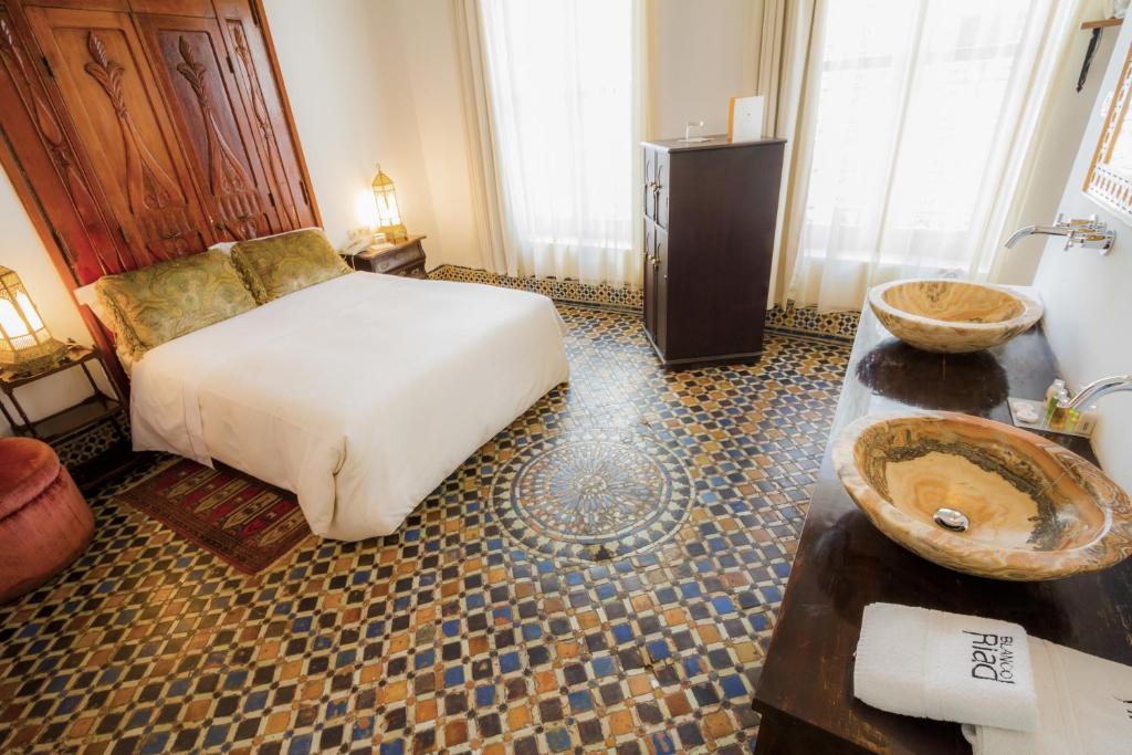a bathroom with a bed and a sink in a room at Hotel Blanco Riad in Tetouan