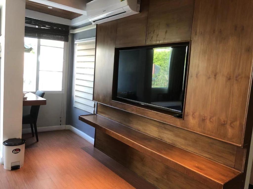 A wood-paneled room corner with television, bench, desk, and window.