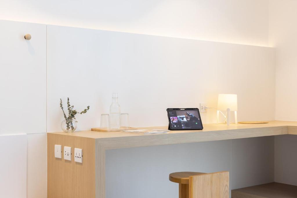 A built-in work desk with a laptop, stool, lamp, and power outlets.