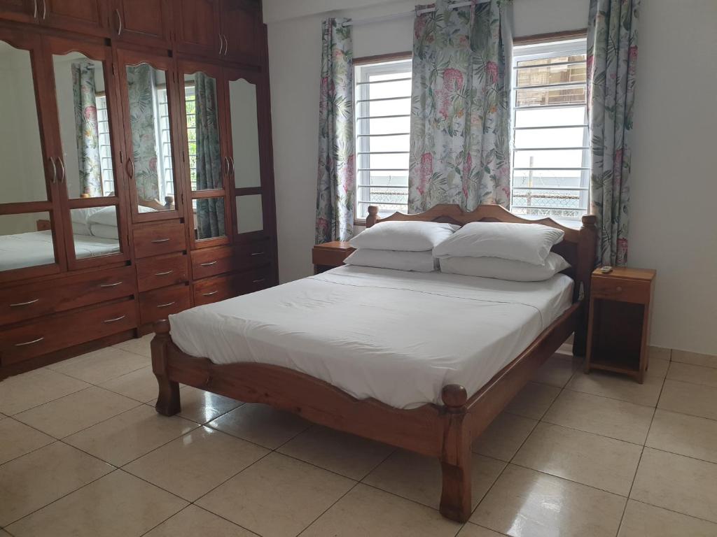 1 dormitorio con 1 cama con sábanas y almohadas blancas en Palmont Commercial Self-Catering Apartments - Beau Vallon, en Beau Vallon
