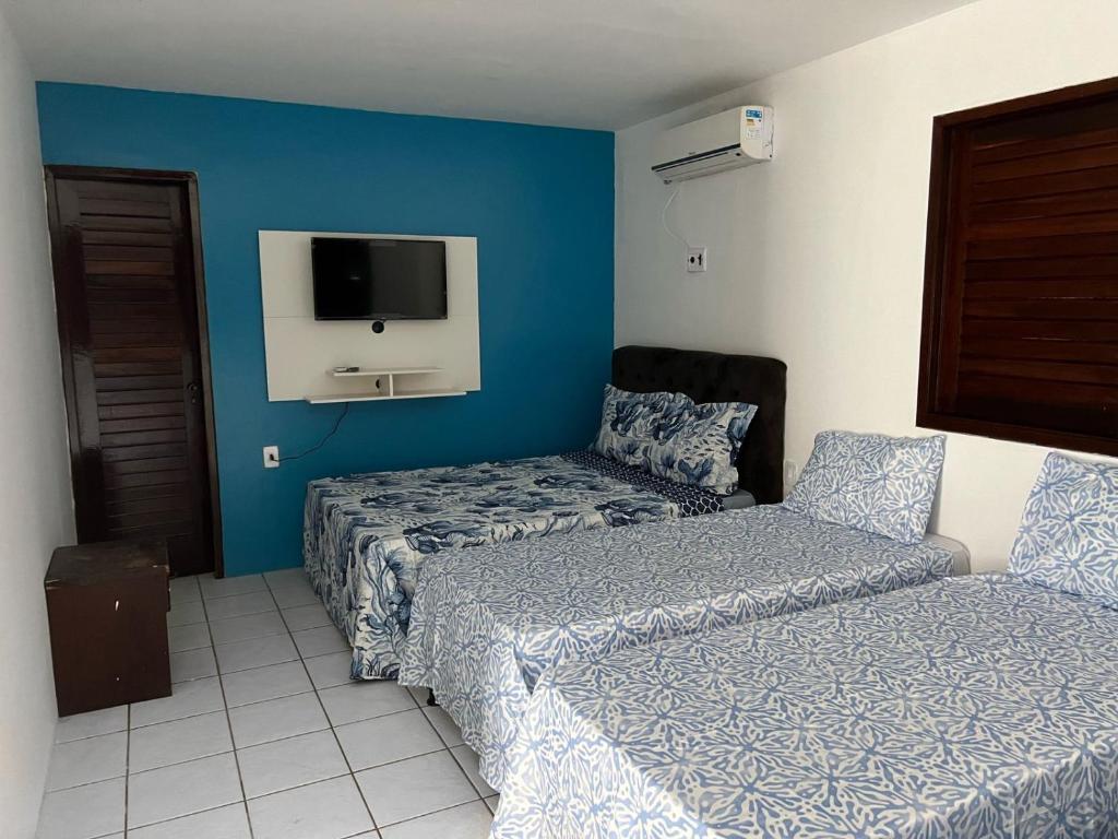 ein Hotelzimmer mit 2 Betten und einem TV in der Unterkunft CASA DE PRAIA PEROBA in Maragogi
