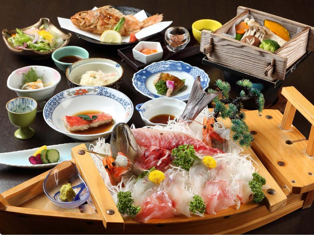 東伊豆的住宿－伊豆溫泉片瀨旅館，桌上装满海鲜和其他食物的木托盘