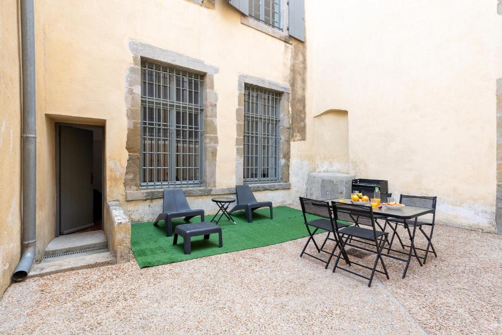 un patio avec des chaises et une table sur un tapis vert dans l'établissement superbe appartement avec cour dans la bastide, à Carcassonne