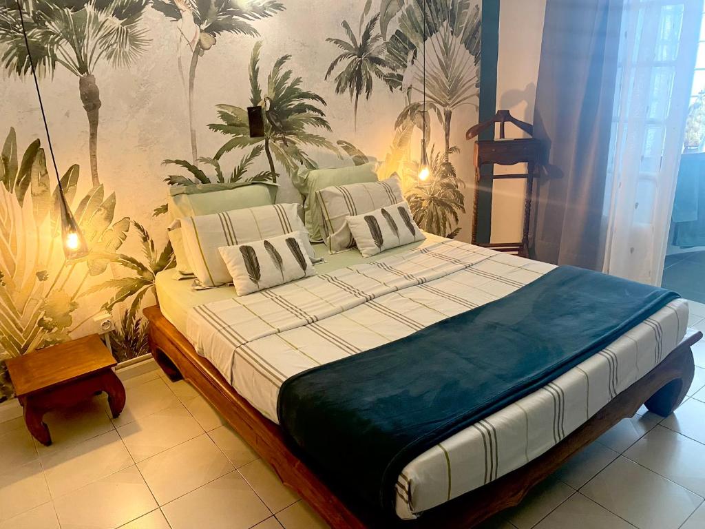 duże łóżko w pokoju z roślinami na ścianie w obiekcie Ti Kaz Lo Ker chambre d'hôte chez l'habitant w mieście Saint-Joseph