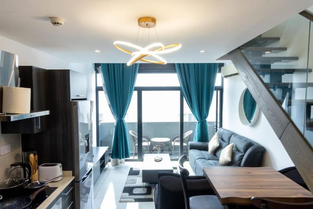 uma sala de estar com um sofá azul e uma ventoinha de tecto em Skyline 1 Bed, Loft 2 @Embassy Gardens em Cantonments