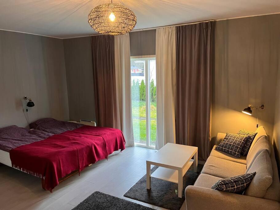 a bedroom with a red bed and a couch at Lägenhet med sjötomt. Vildmark i tätort. in Umeå