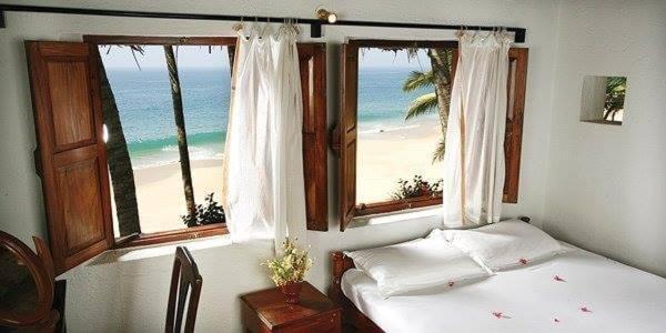 a bedroom with a bed and a view of the beach at Karikkathi Beach House in Trivandrum