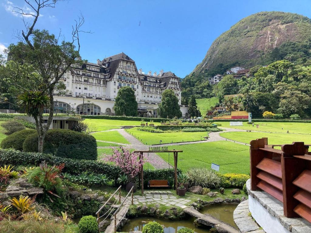 um edifício com um jardim em frente a uma montanha em Apartamento aconchegante no Hotel Quitandinha em Petrópolis