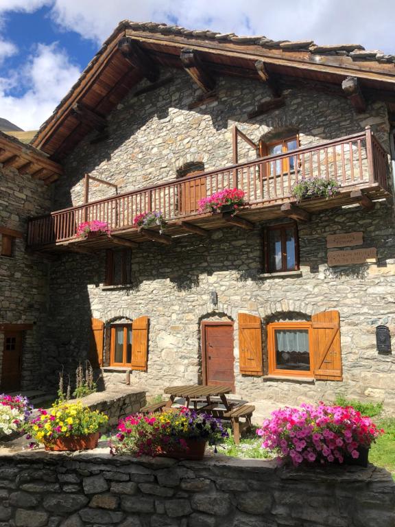 a stone house with a balcony and flowers in front of it at Chalet 3 Céline 6 personnes Vieux Village in Bonneval-sur-Arc