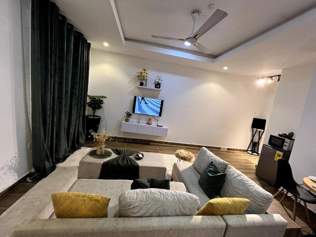a living room with a couch and a flat screen tv at Cozy minimal suite in Accra